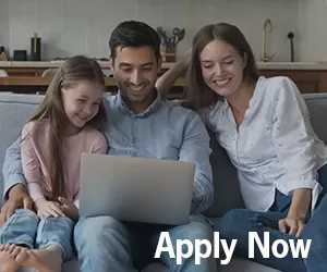 family of three looking at laptop on couch with kitchen in backgroun
