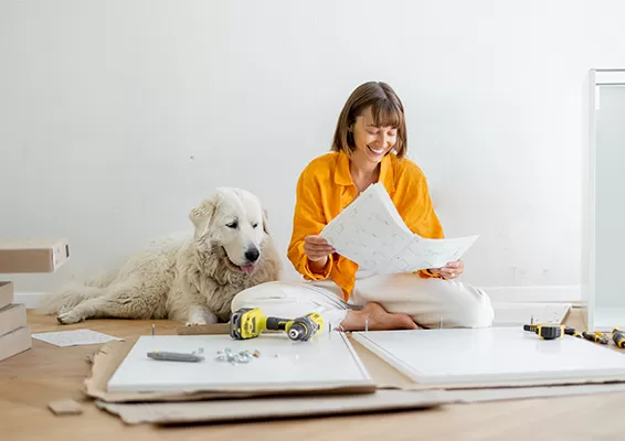 woman and dog looking at blue prints with drill and other home improvement items
